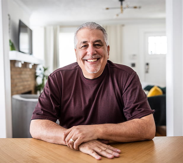 Un hombre sentado en la mesa de comer en un hogar elegantemente alumbrado por luz natural.