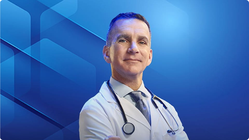 Dr Chuck Vega, MD, in a white coat and stethoscope, smiling with arms crossed.