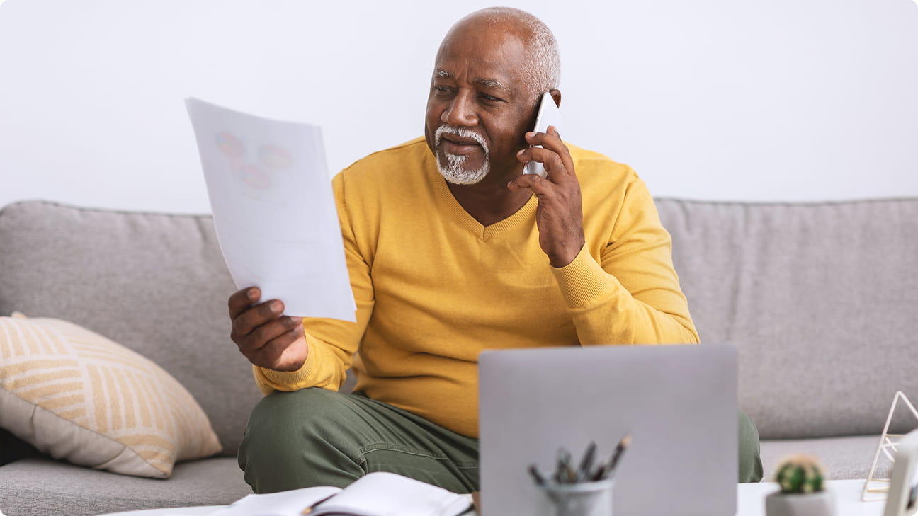 A man looking at his test results while on the phone with his doctor.