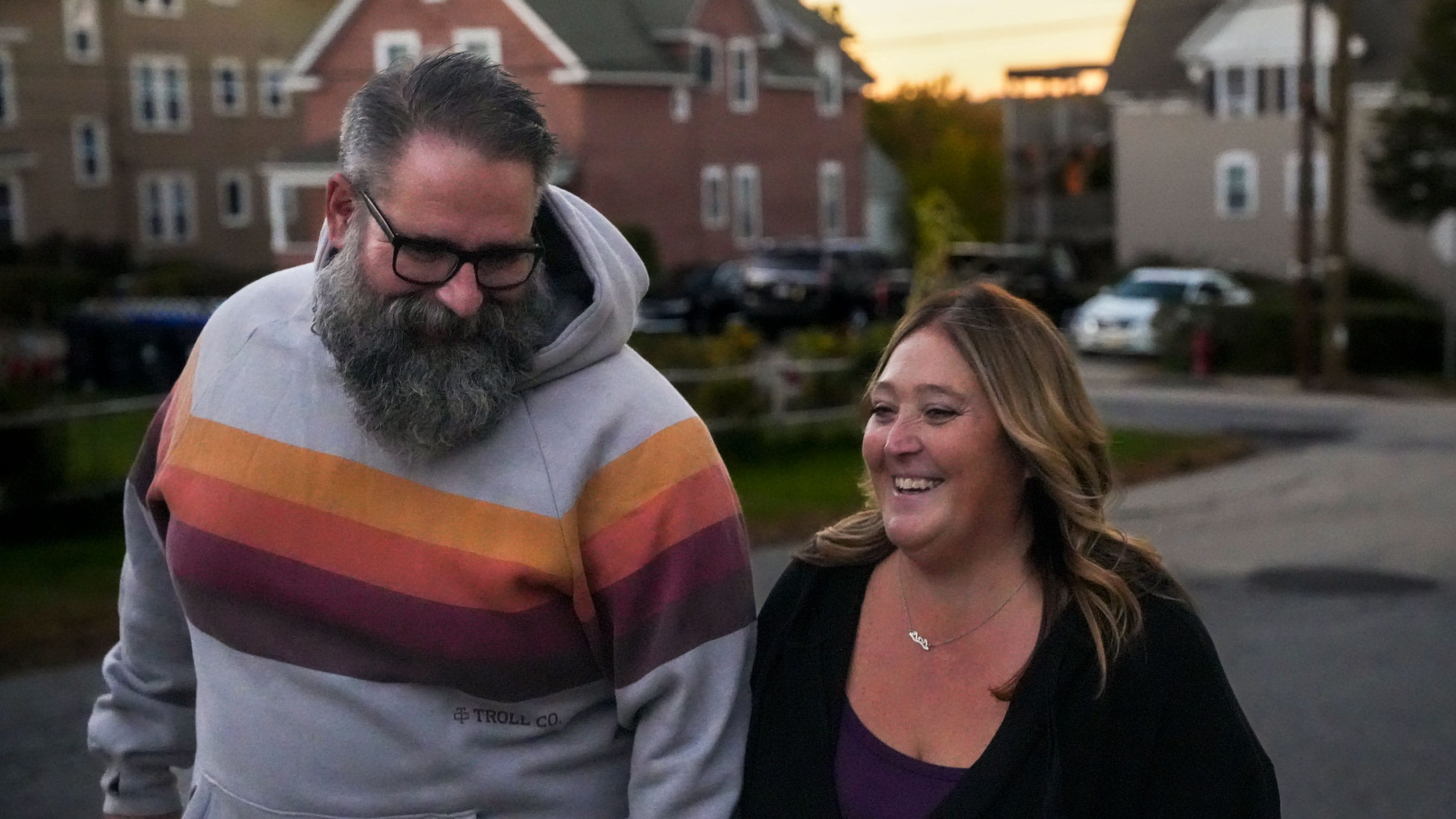 Tim smiling and walking side by side with a woman on a street.