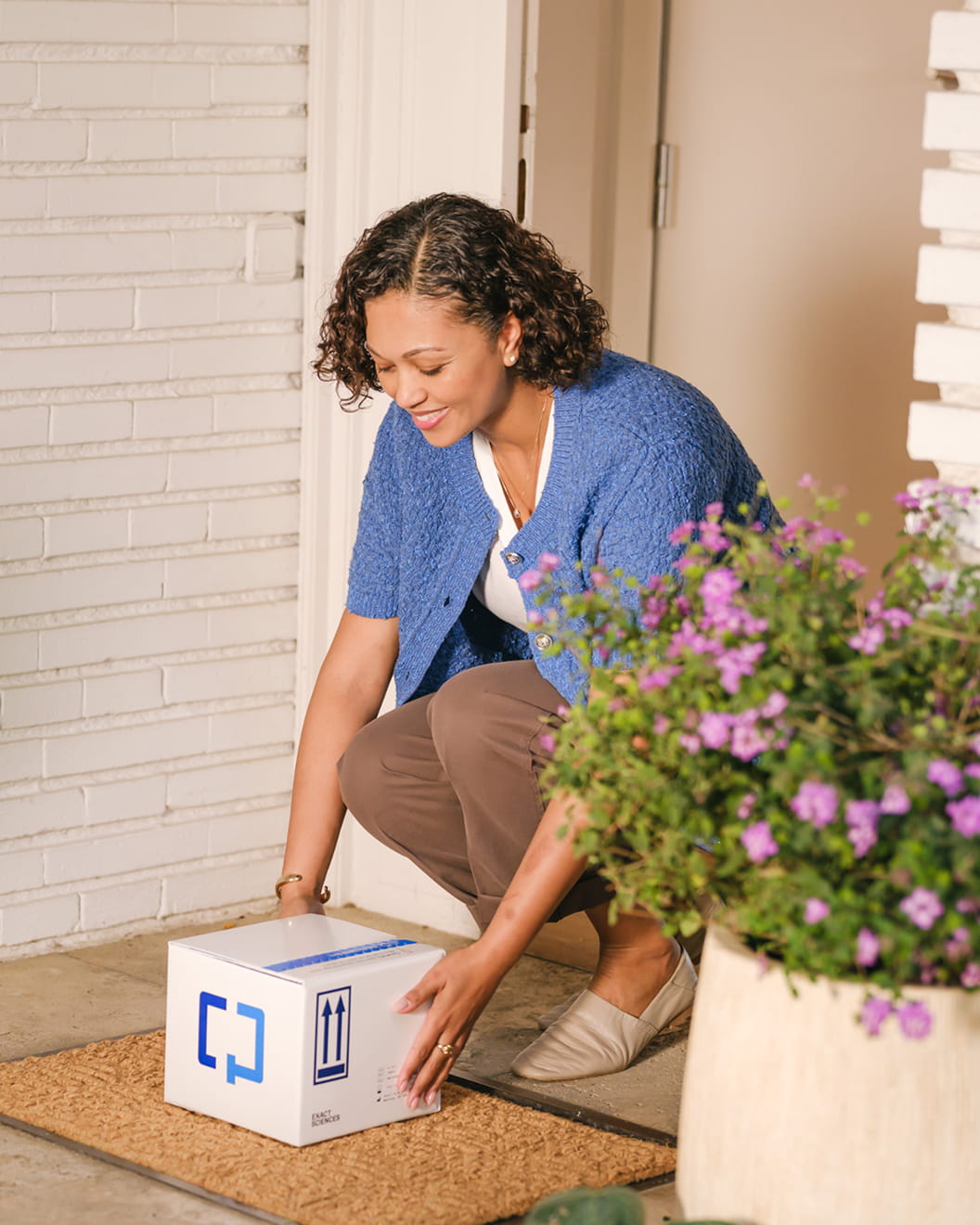  A woman picks up a Cologuard Plus box that’s just been delivered to her door.