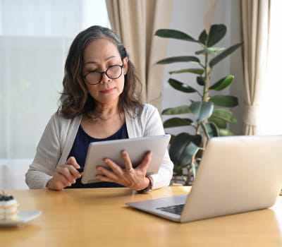 A woman sitting at a table looking at a tablet