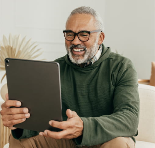 Un hombre sentado en un sofá y leyendo una tableta digital.