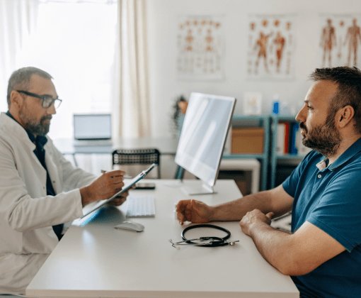 A man and a healthcare provider having a conversation while sitting at a desk