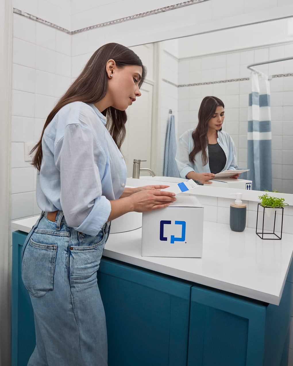 A woman prepares to use a Cologuard Plus box in her bathroom.