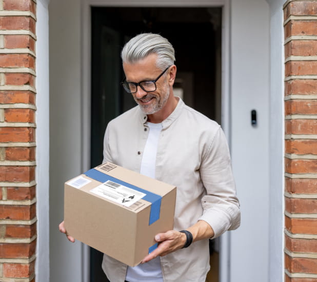 A man standing at a doorstep holding a package