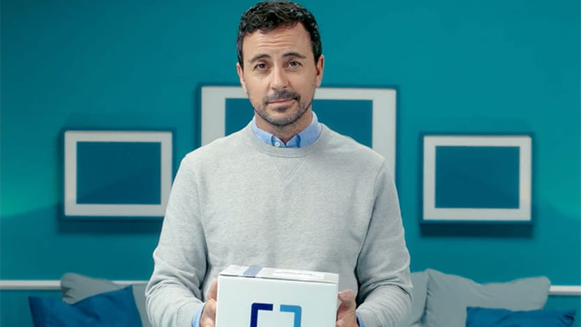 A man stands in his living room holding a Cologuard box.