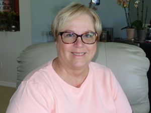 Nancy headshot sitting in chair with pink shirt