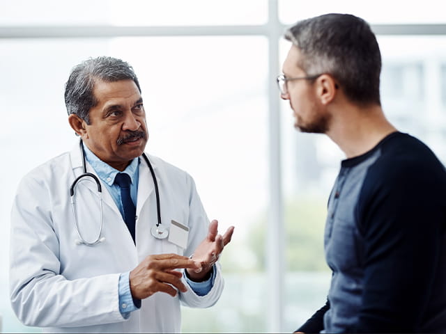 Un doctor le explica detalles sobre la salud a un hombre durante su consulta médica.