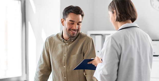 Un hombre mira el documento que una doctora le muestra en su consultorio médico.