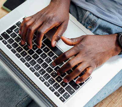 Un hombre escribiendo en el teclado de una laptop.